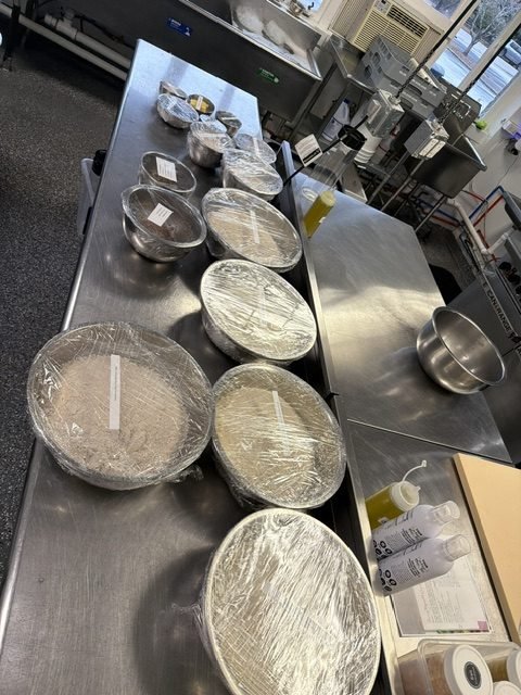 Covered mise-en-place lined up along the bench