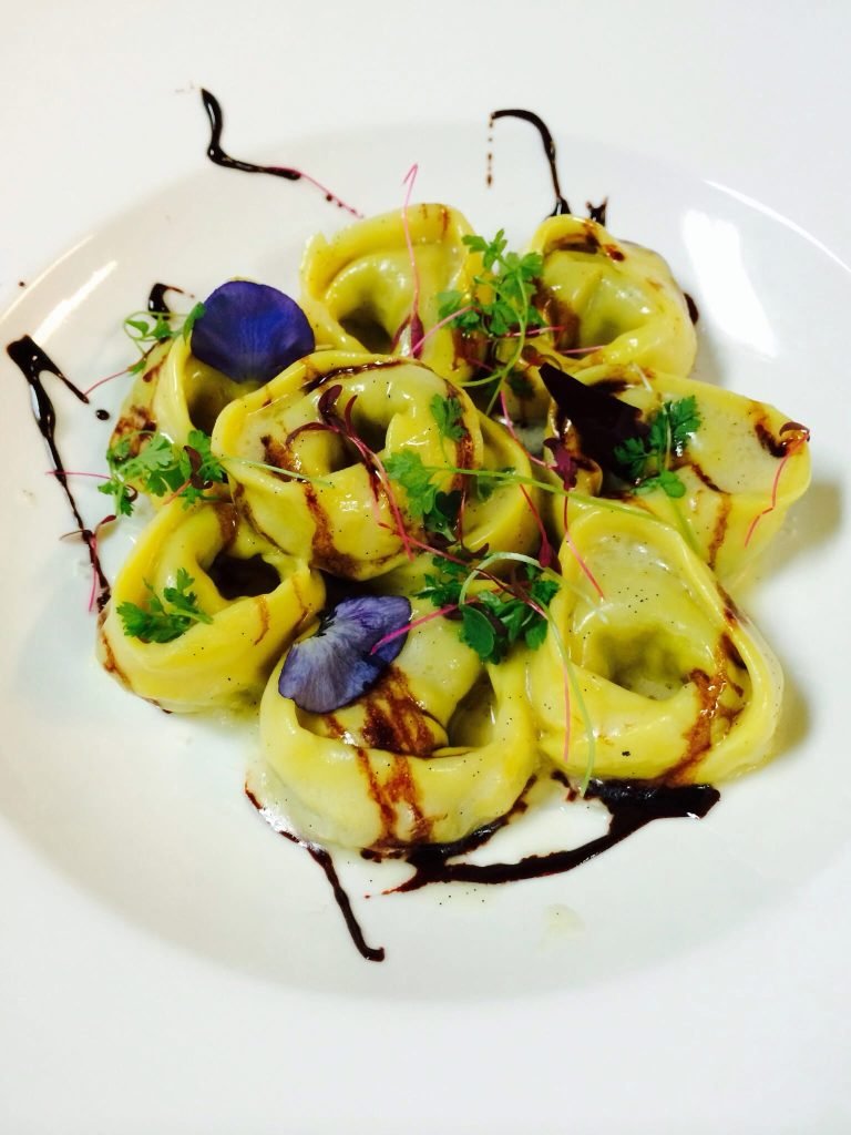 Saffron tortellini dressed with herbs and flowers