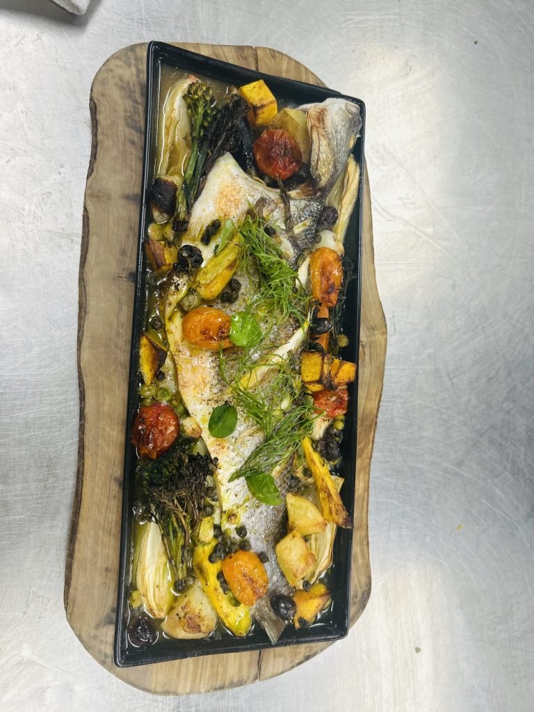A whole fish roasted over fennel, squash and tomatoes