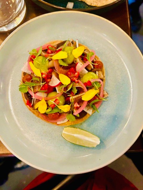 A tostada dressed with pickled onion, herbs and lime